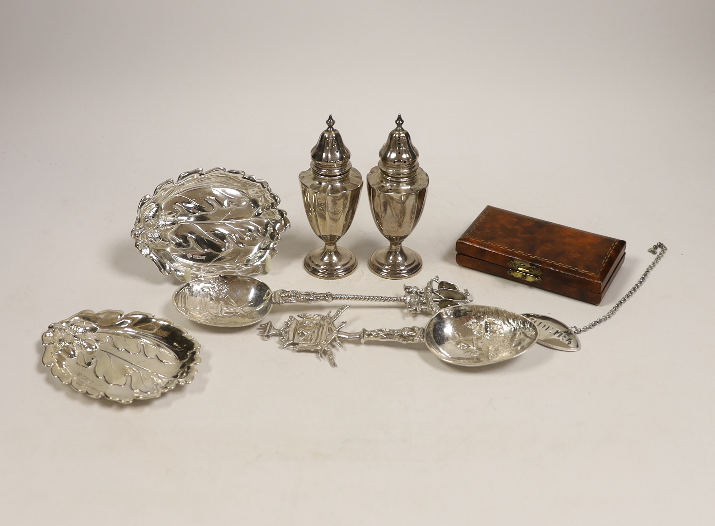 Small silver including a pair of Edwardian silver pepperettes, London, 1906, two continental import marked silver spoons, a silver dish, Georgian wine label and a cased set of four silver and enamel bridge pencils, impor